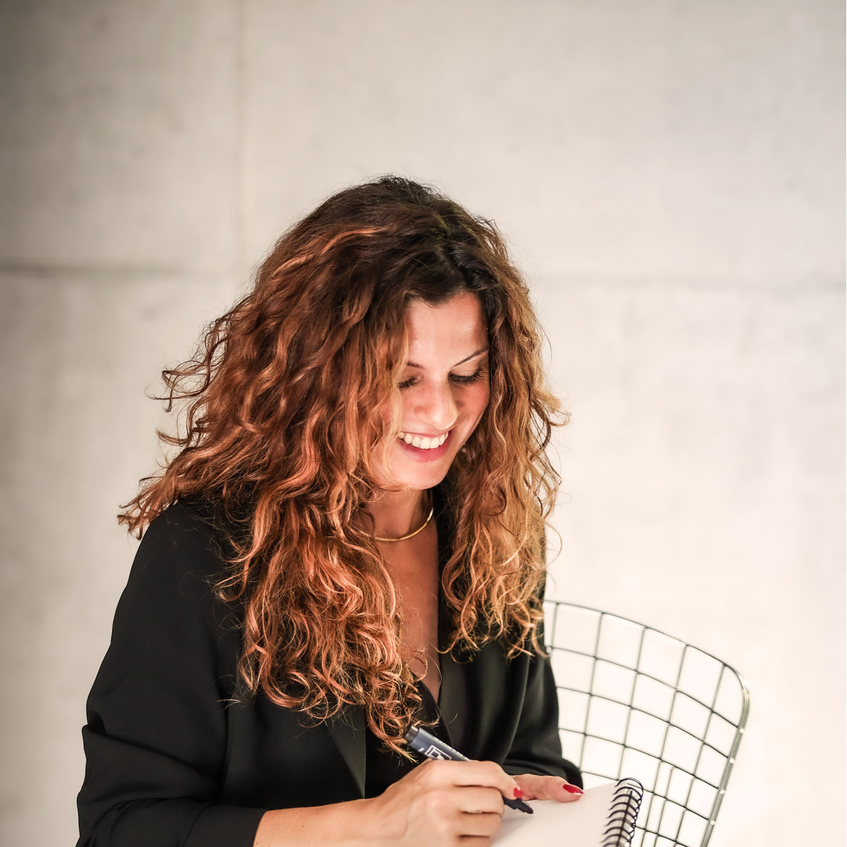Sophie Di Martino, souriante, prend des notes dans un carnet